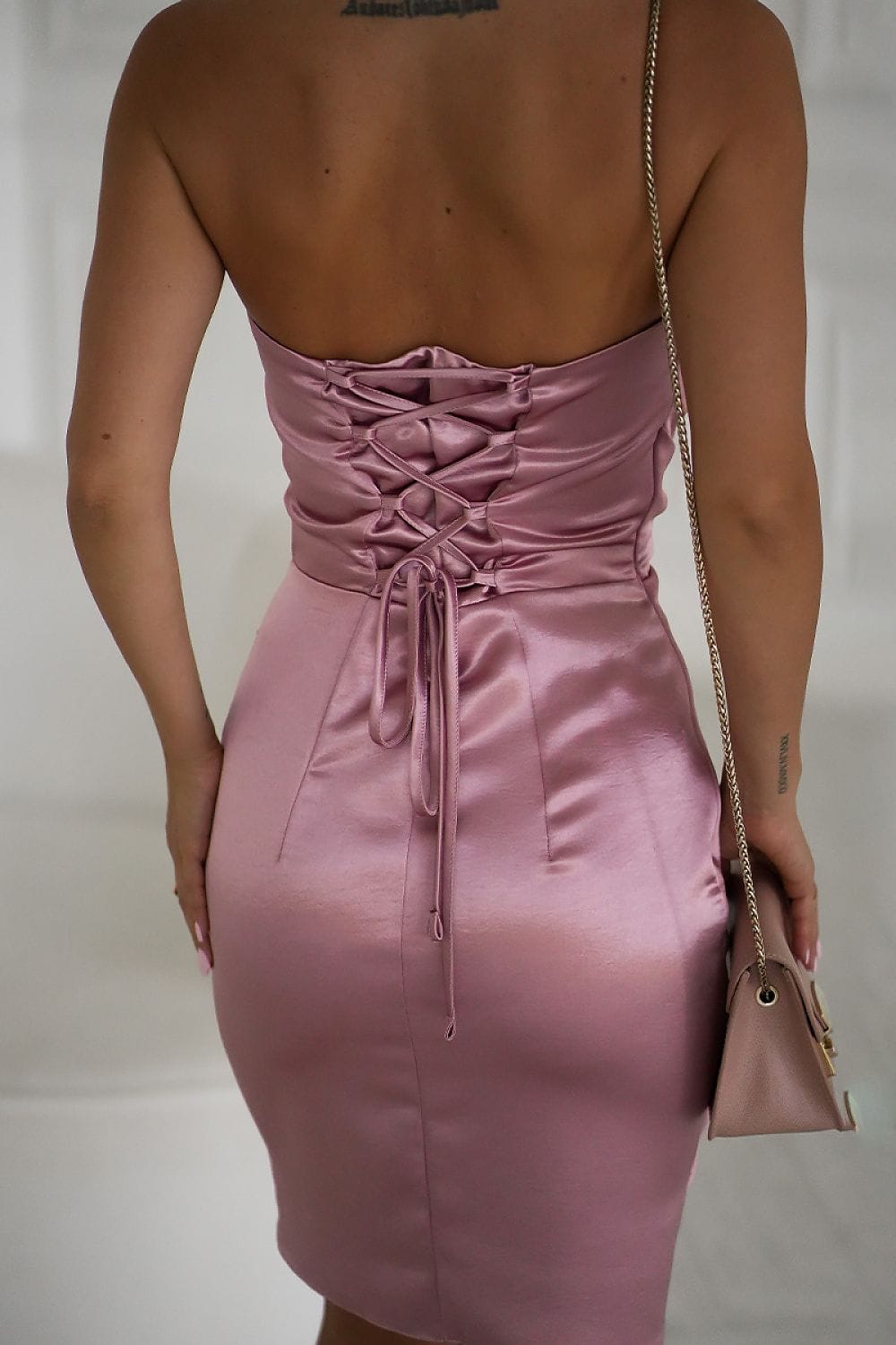 Robe courte satinée rose moulante dos nu soirée chic avec laçage au dos et sac à bandoulière dorée