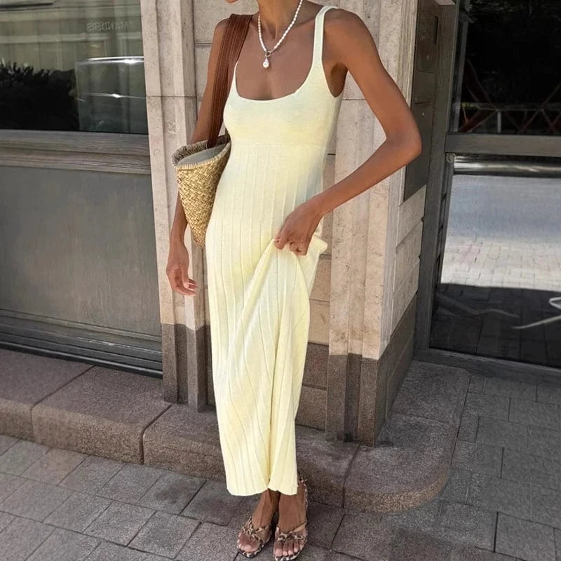 Robe longue été fluide en maille jaune sans manches, style casual chic, accessoirisée d’un sac en paille