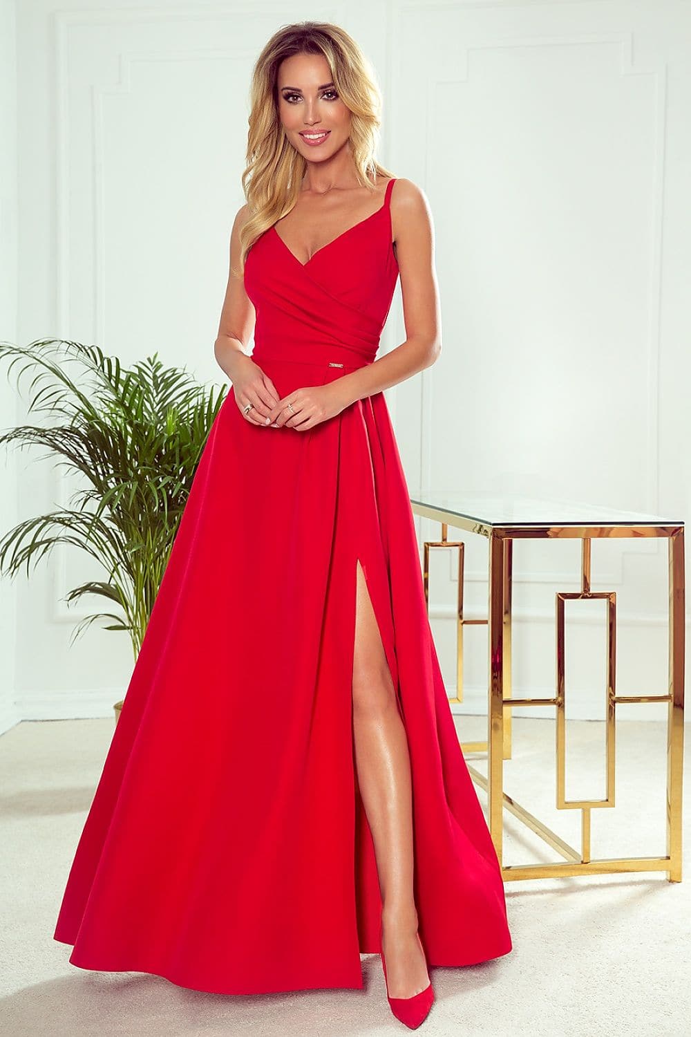 Robe de soirée rouge longue fendue, élégante pour gala ou mariage, avec décolleté en V et sans manches, silhouette droite.