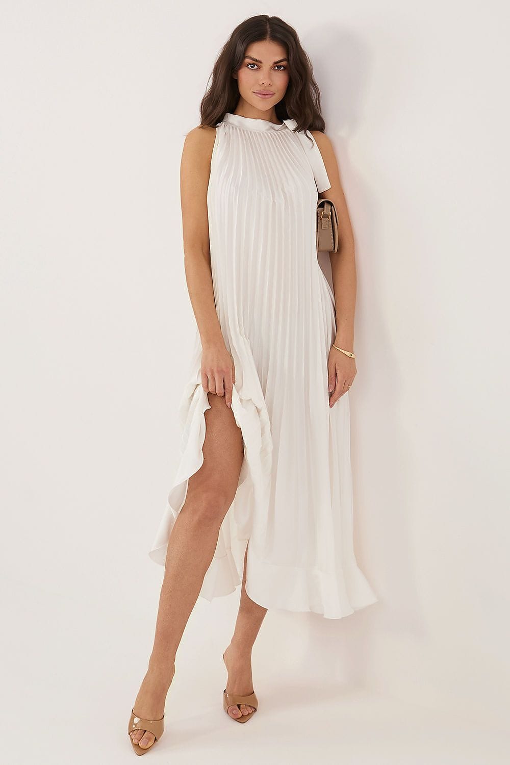 Robe longue blanche plissée sans manches pour soirée chic été, style fluide fendue, femme accessoirisée sac