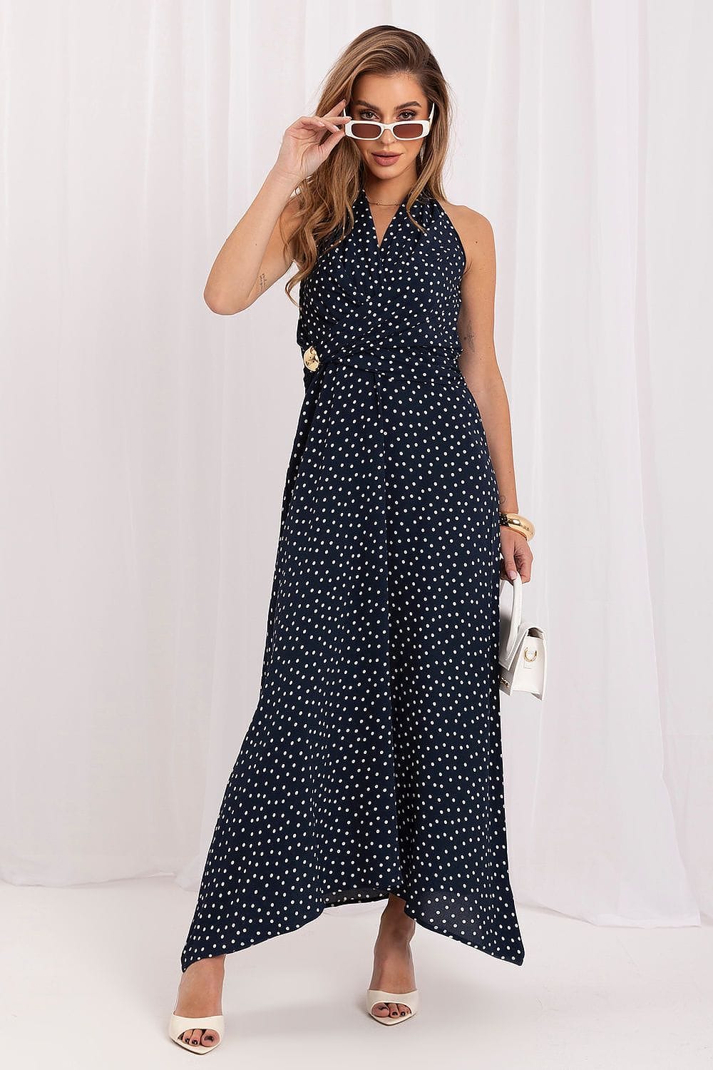 Robe longue bleu à pois style été évasée sans manches chic avec sac à main blanc et lunettes tendance