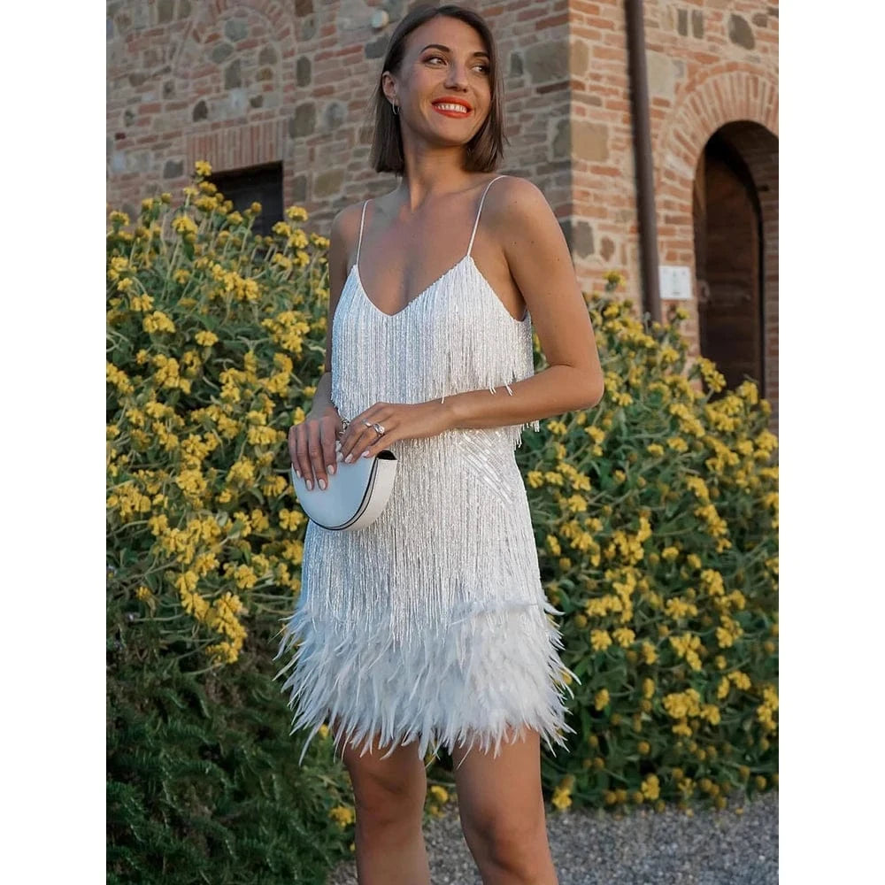 Robe de soirée chic courte blanche à franges et plumes, look cocktail élégant avec pochette blanche assortie