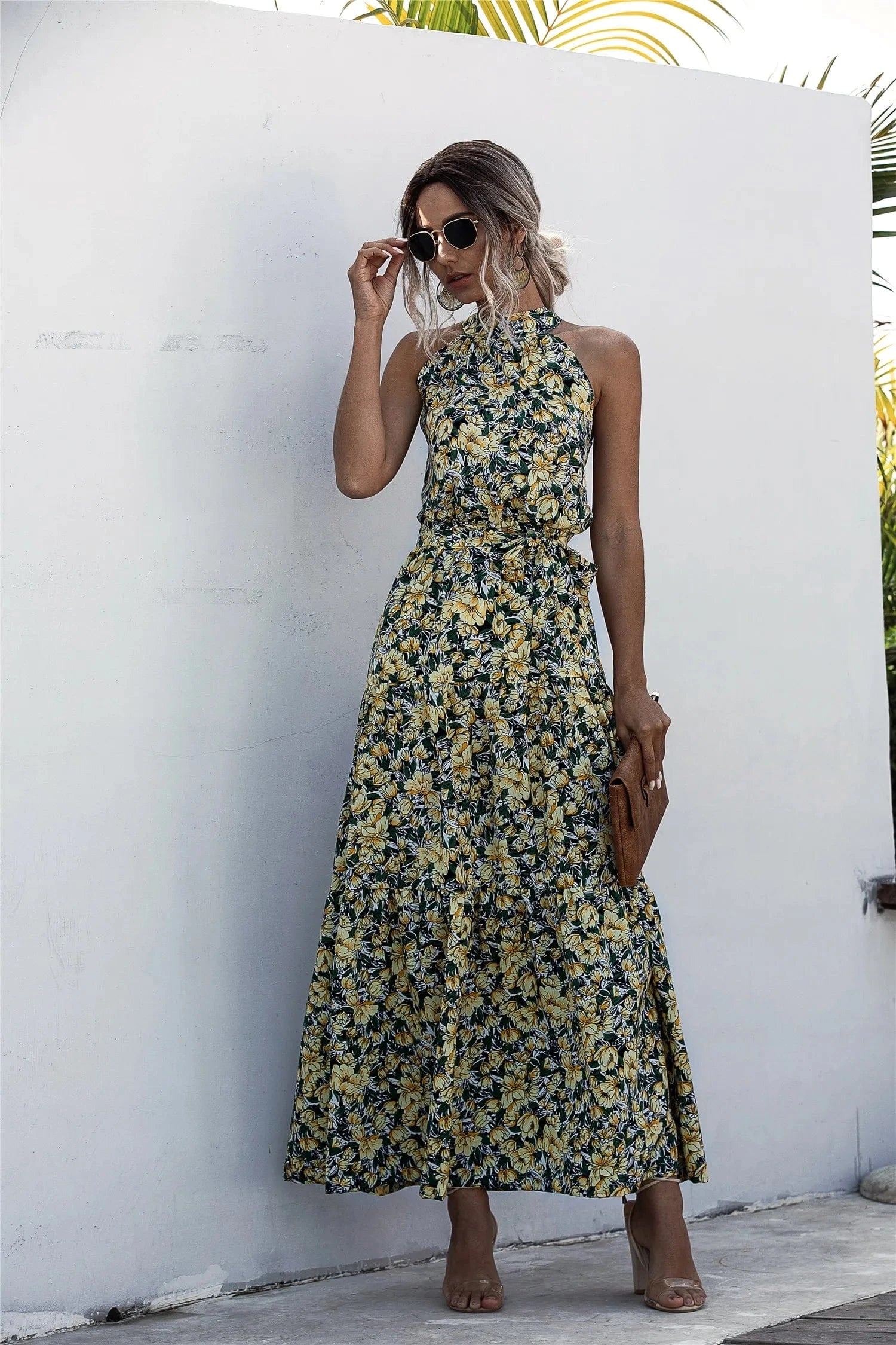 Robe bohème été longue fleurie sans manches pour plage ou mariage invité chic, fond mur blanc et accessoires vintage