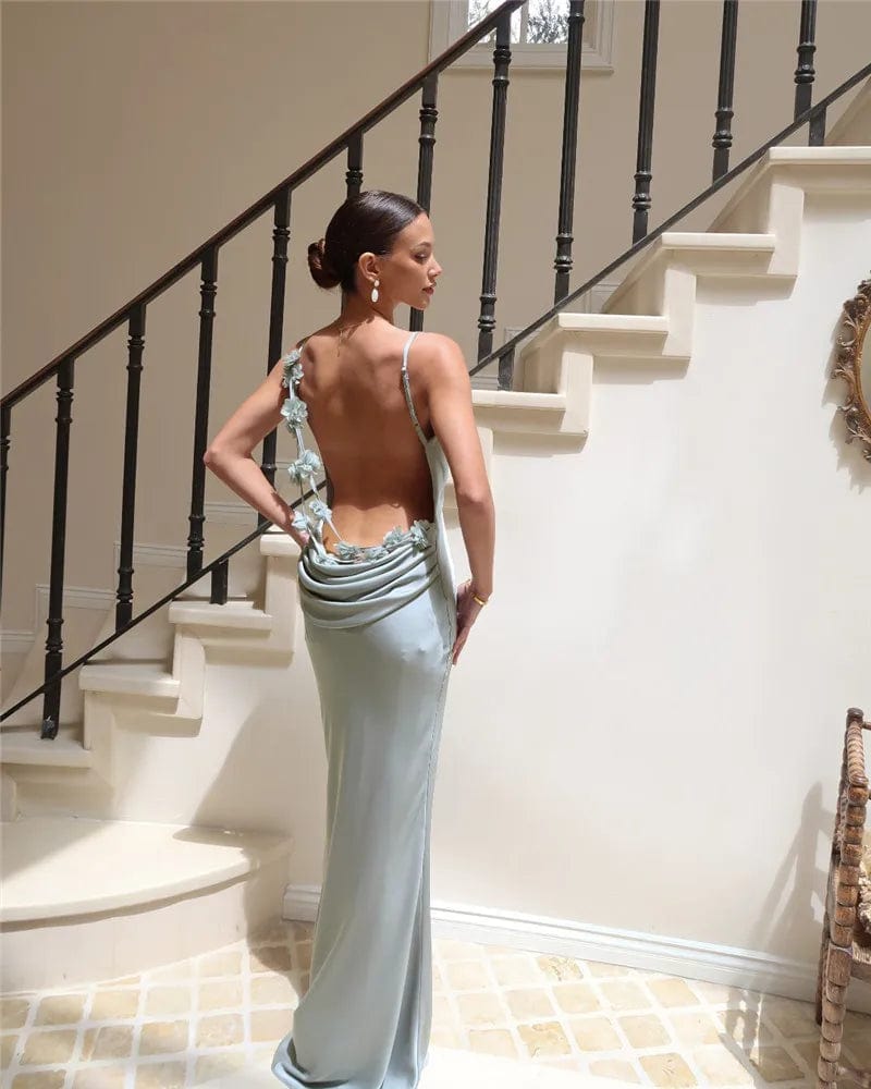 Robe longue dos nu vert sauge avec bretelles spaghetti pour soirée chic, silhouette moulante et détails fleuris.