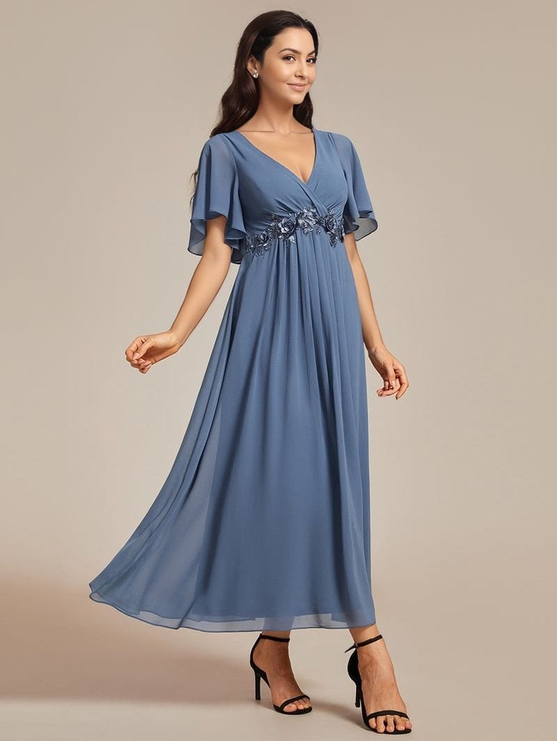 Robe de soirée longue bleu fluide chic avec manches courtes et détails fleuris à la taille pour mariage invité