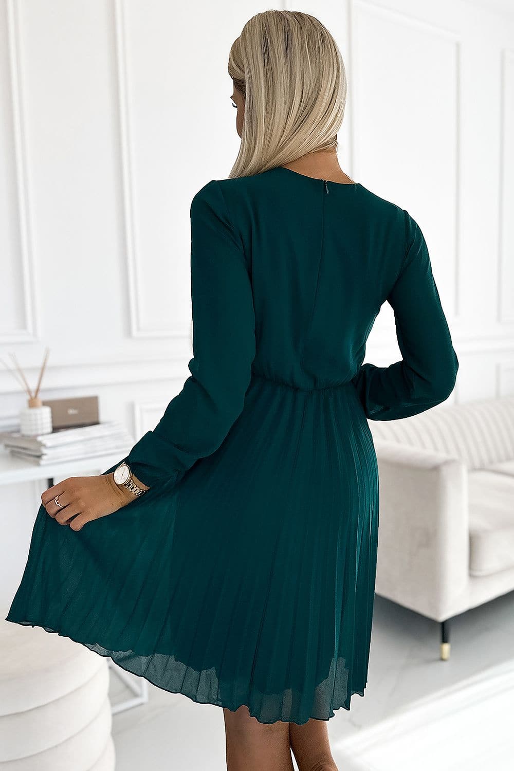 Robe verte courte chic à manches longues pour soirée, avec une silhouette trapèze et plissée, idéale pour cocktail ou événement élégant.