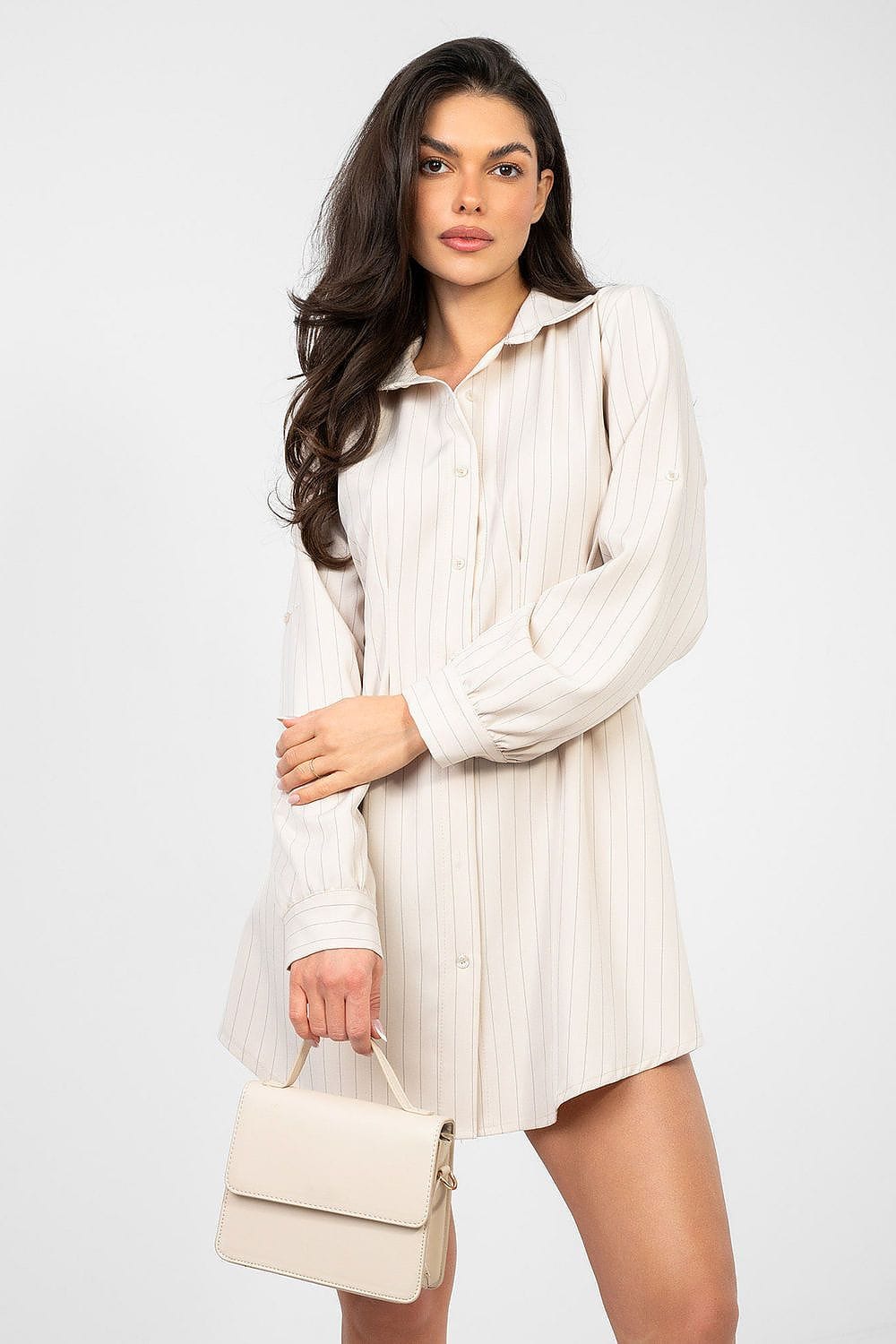 Robe chemise courte manches longues beige à rayures pour look casual chic, accessoirisée d’un sac à main élégant