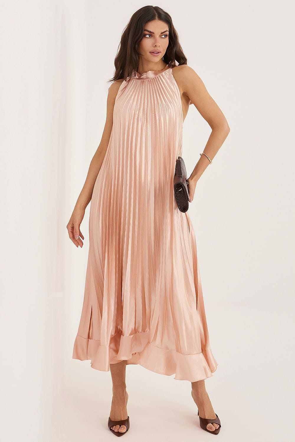 Robe cocktail satin plissée longue rose poudré sans manches, accessoirisée d’une pochette, élégante soirée