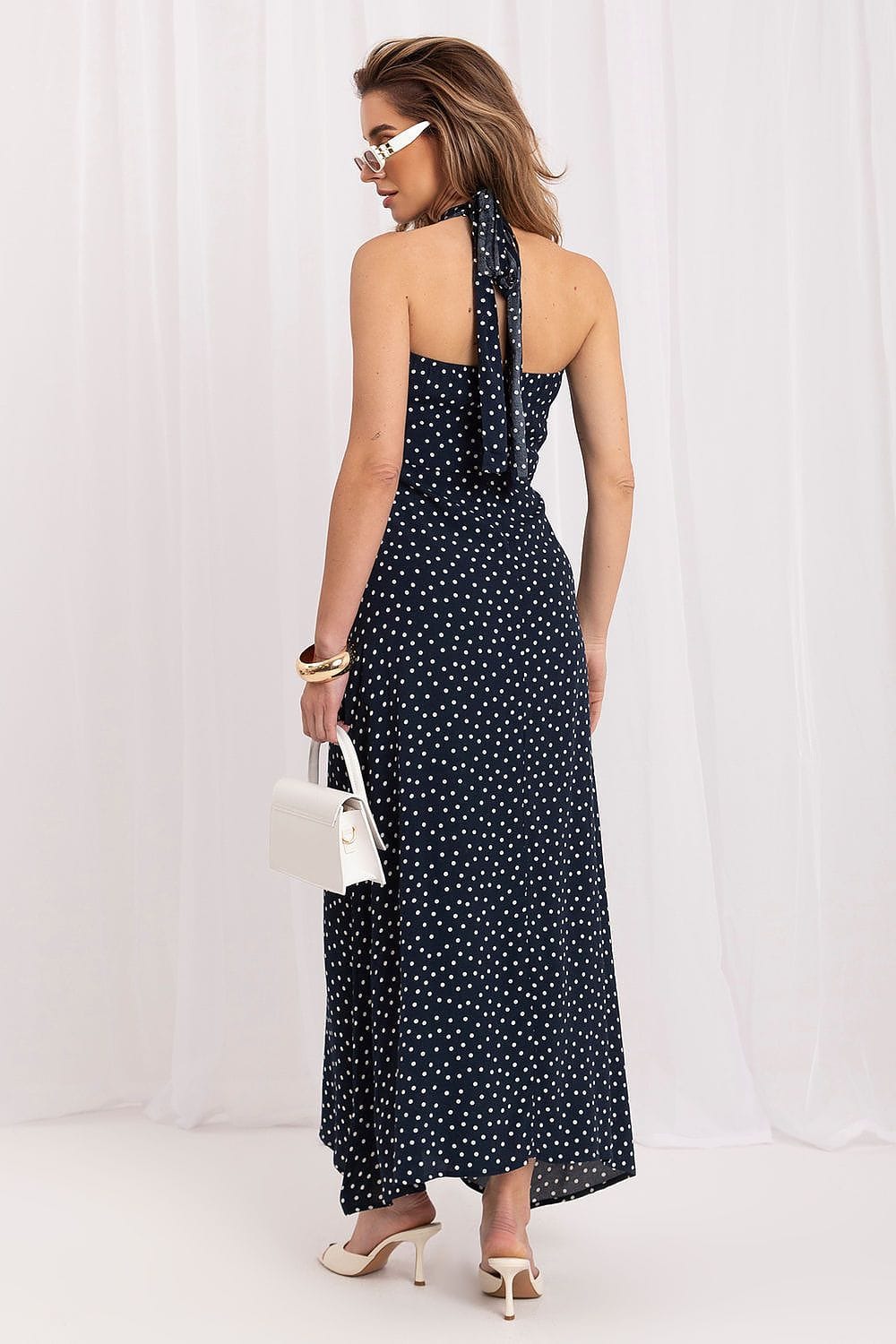 Robe longue bleue à pois blancs style été dos nu élégante, parfaite pour une soirée chic, accessoirisée sac blanc