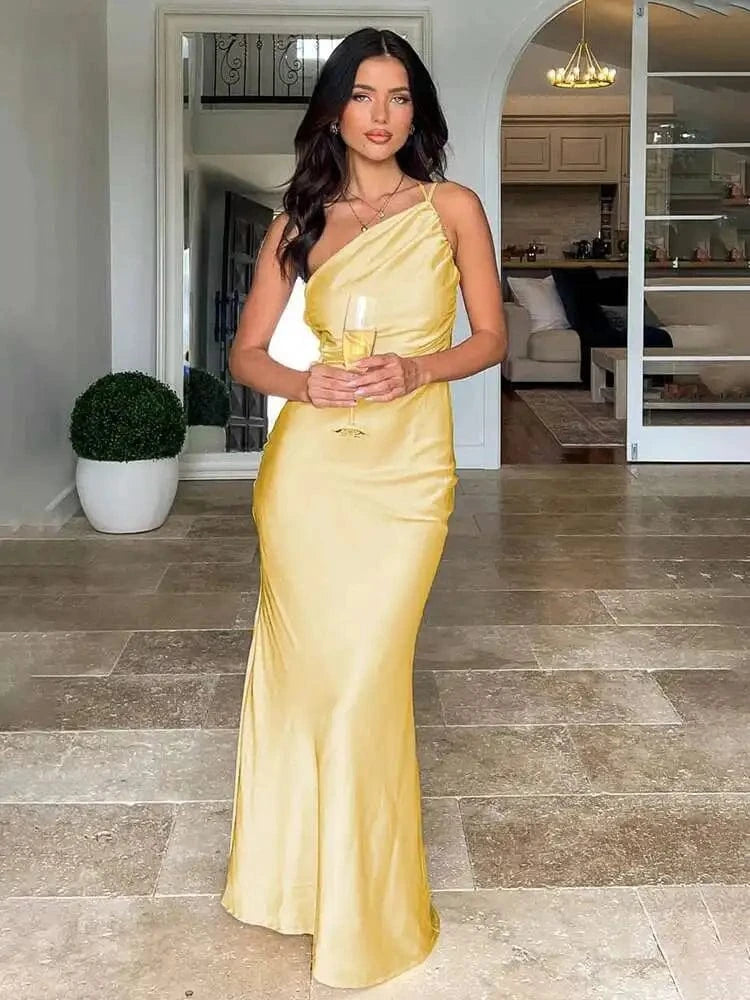 Robe de soirée chic longue dorée moulante sans manches décolleté élégant femme tenant un verre dans salon