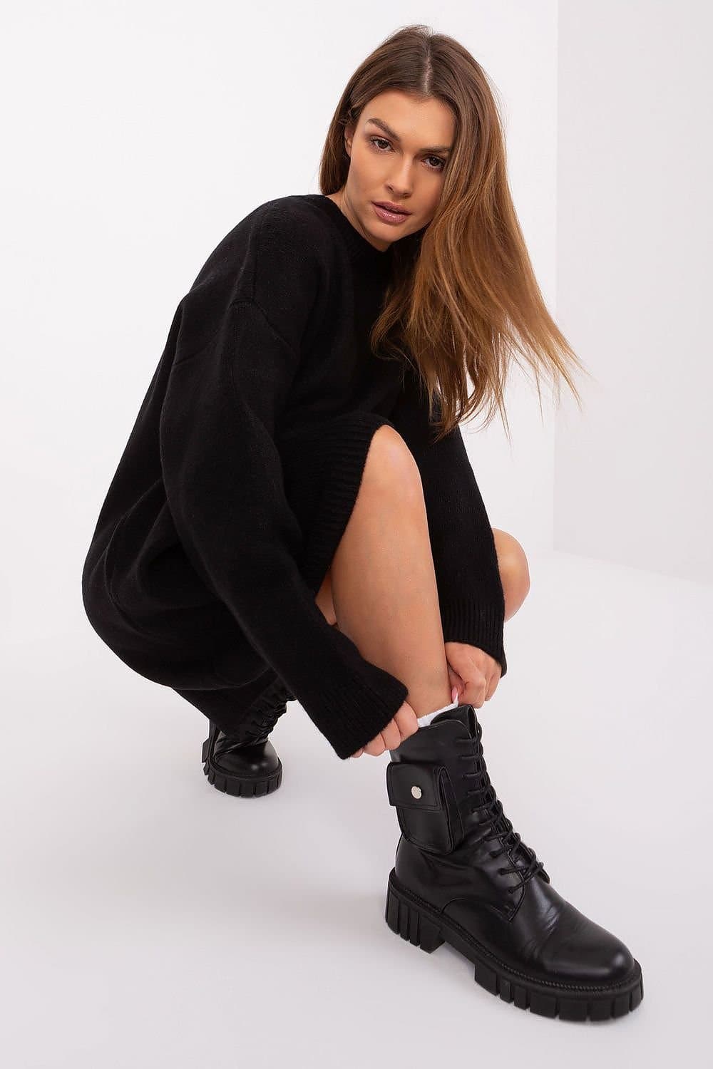 Robe pull oversize noire manches longues pour un look casual et confortable, idéale en hiver avec bottes robustes.